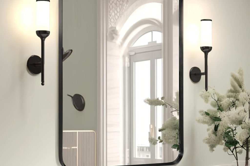 Brushed black metal wall-mounted vanity mirror with rounded corners in a modern bathroom