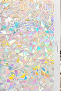 “Homein rainbow decorative window privacy film with 3D stained-glass look applied to a living room window, casting colorful light indoors.”