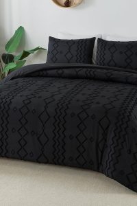 Black tufted queen comforter set with geometric pattern and two matching pillowcases on a modern farmhouse bed.
