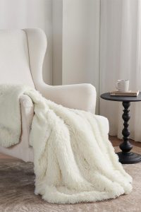 Bedsure fluffy cream Sherpa throw blanket draped over a cozy couch
