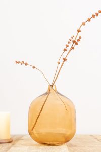 Bloomingville modern amber tinted glass vase placed on a minimalist wooden table.
