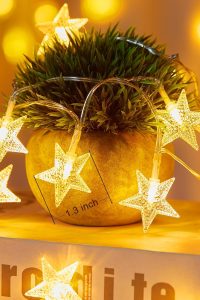 Battery-operated 17 ft warm white star string lights decorating a bedroom wall and canopy bed