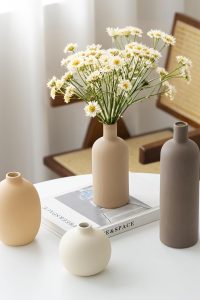 Set of four neutral-toned ceramic vases in coffee, beige, and taupe on a wooden shelf.