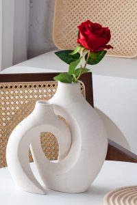 Set of 2 off-white hollow ceramic donut vases styled on a coffee table with dried pampas grass.