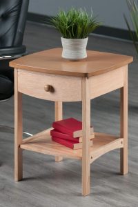 Natural wood 18-inch Winsome Claire accent table with drawer and lower shelf in a cozy living room corner