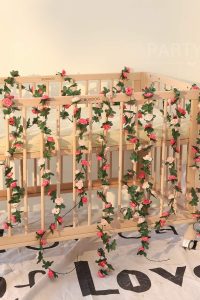 “Pink artificial rose flower garlands hanging on garden wall”