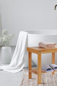 "VaeFae bamboo shower bench with non-slip feet and storage shelf, used as spa stool, shaving seat, or footrest in bathroom or bedroom"