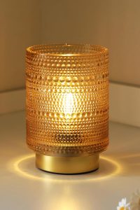 Golden cordless LED decorative lamp on a wooden bedside table, warm light glow