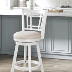 “Hillsdale Fairfox White Swivel Stool with Lattice Back next to a kitchen island”