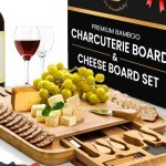 Bamboo charcuterie board with knives and serving set displayed with cheese and fruit