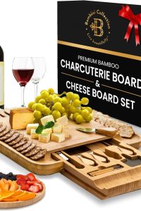 Bamboo charcuterie board with knives and serving set displayed with cheese and fruit