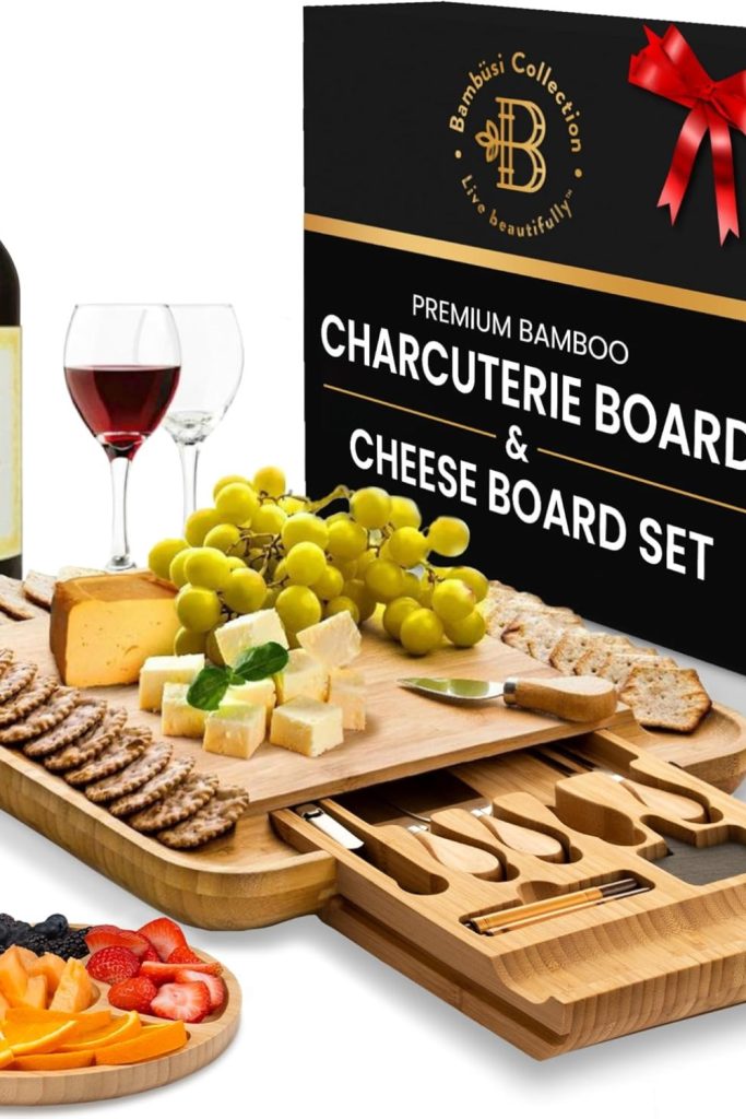 Bamboo charcuterie board with knives and serving set displayed with cheese and fruit