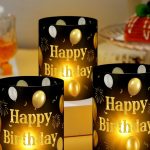 Black and gold Happy Birthday centerpiece lantern box with tea light candle on table.