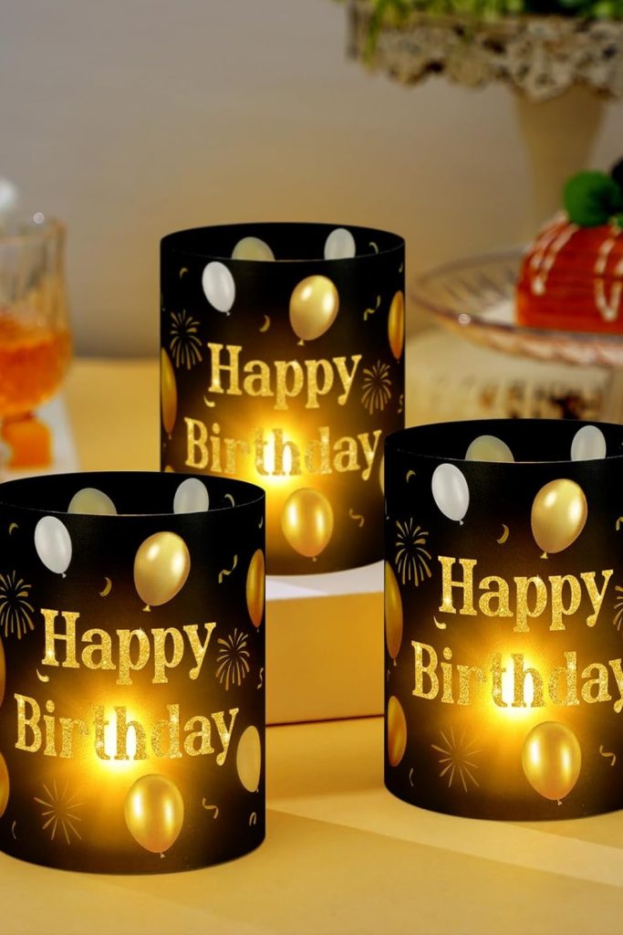 Black and gold Happy Birthday centerpiece lantern box with tea light candle on table.