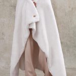 UGG Euphoria Plush Faux Fur Throw Blanket in White Snow draped over couch