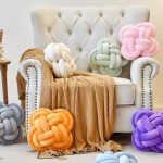Xuyier 12-inch beige knot pillow ball on a modern living room couch