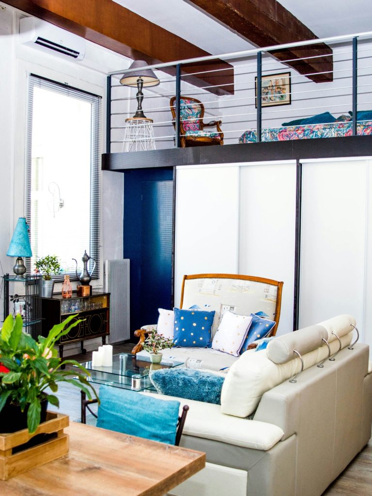 Cozy loft space with layered rugs, cushions, and functional furniture