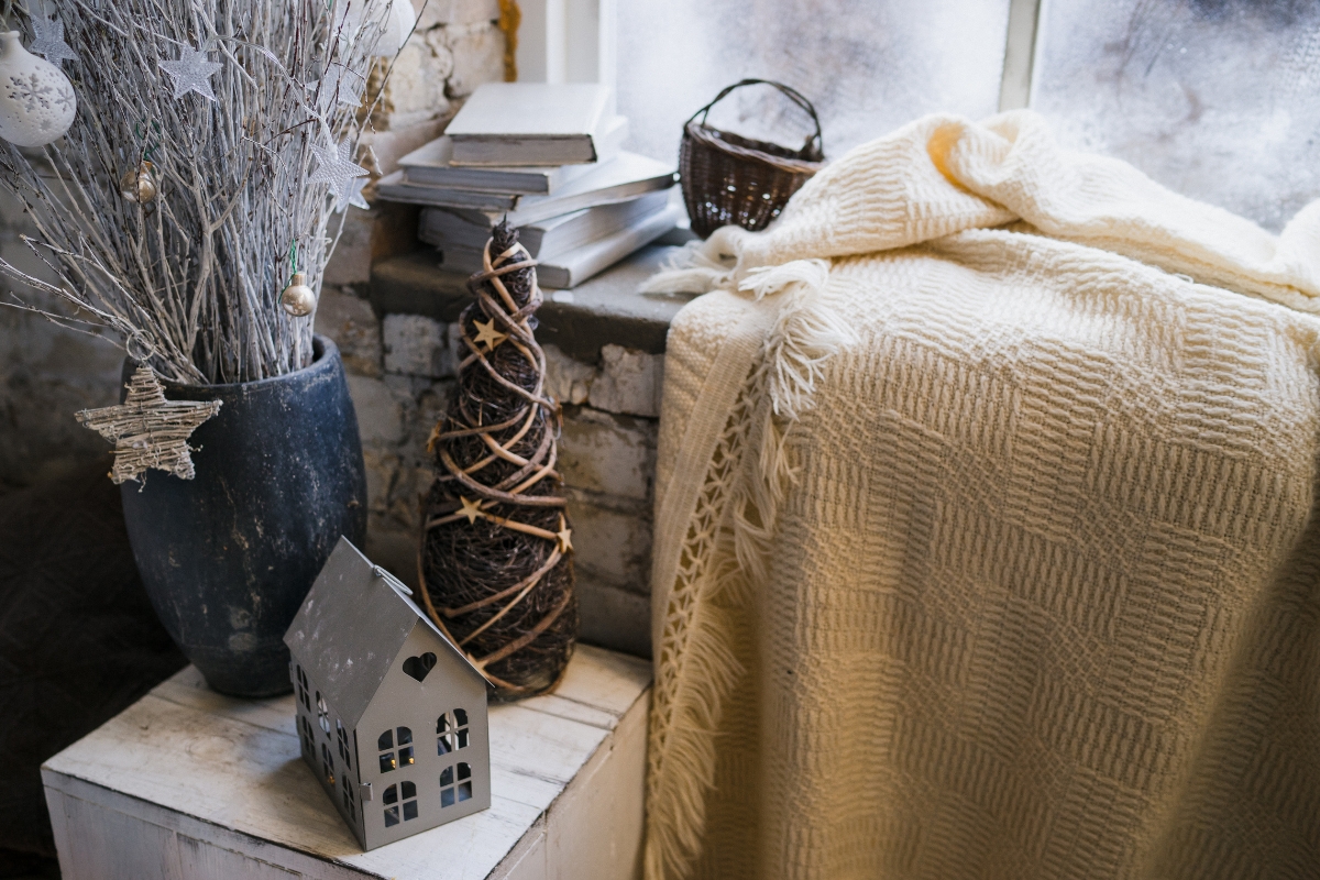 Cozy winter living room with layered textures including knit blankets, velvet pillows, and faux fur rugs.