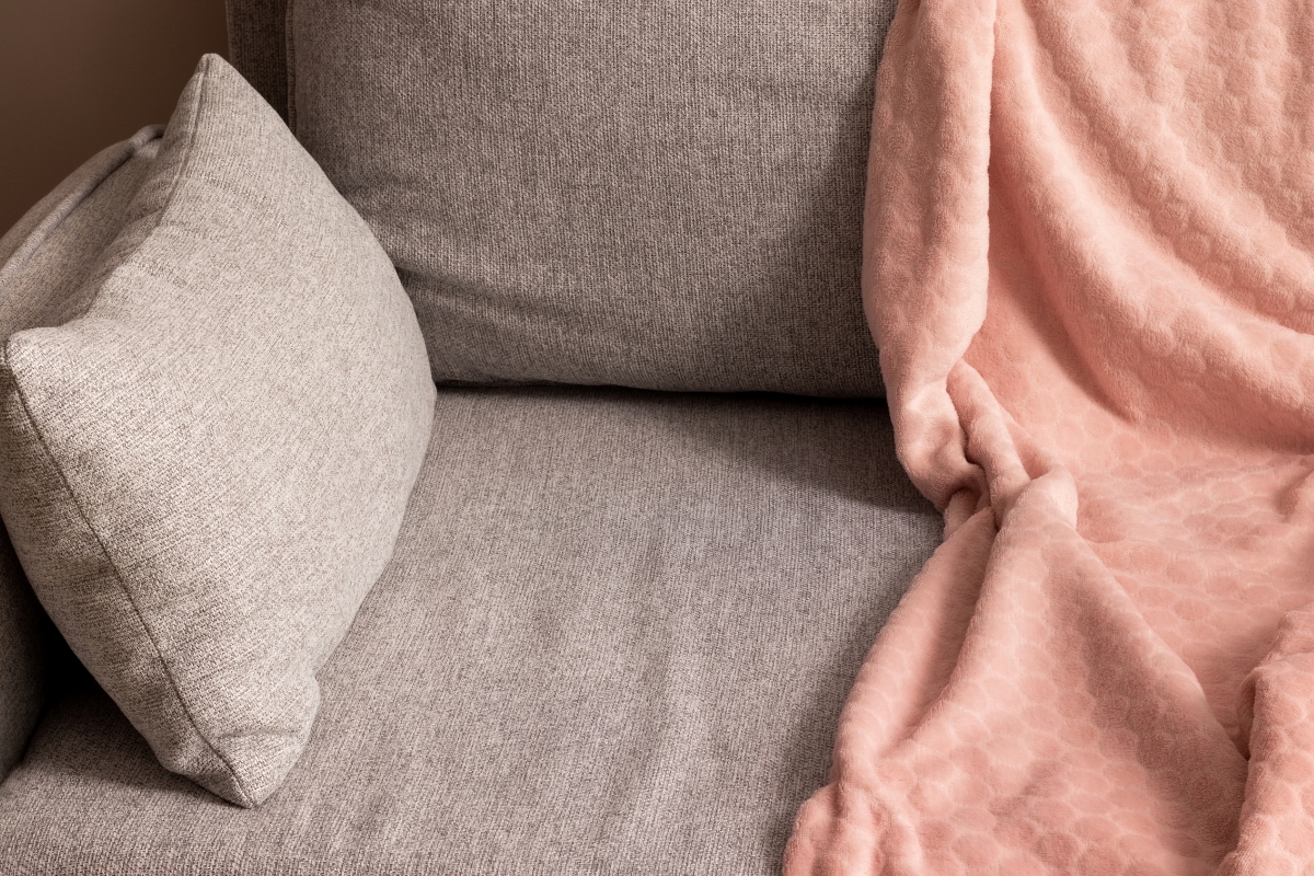 Modern living room with fabric-upholstered sofa, wooden coffee table, and metal accents, layered with cushions and a throw for comfort and style