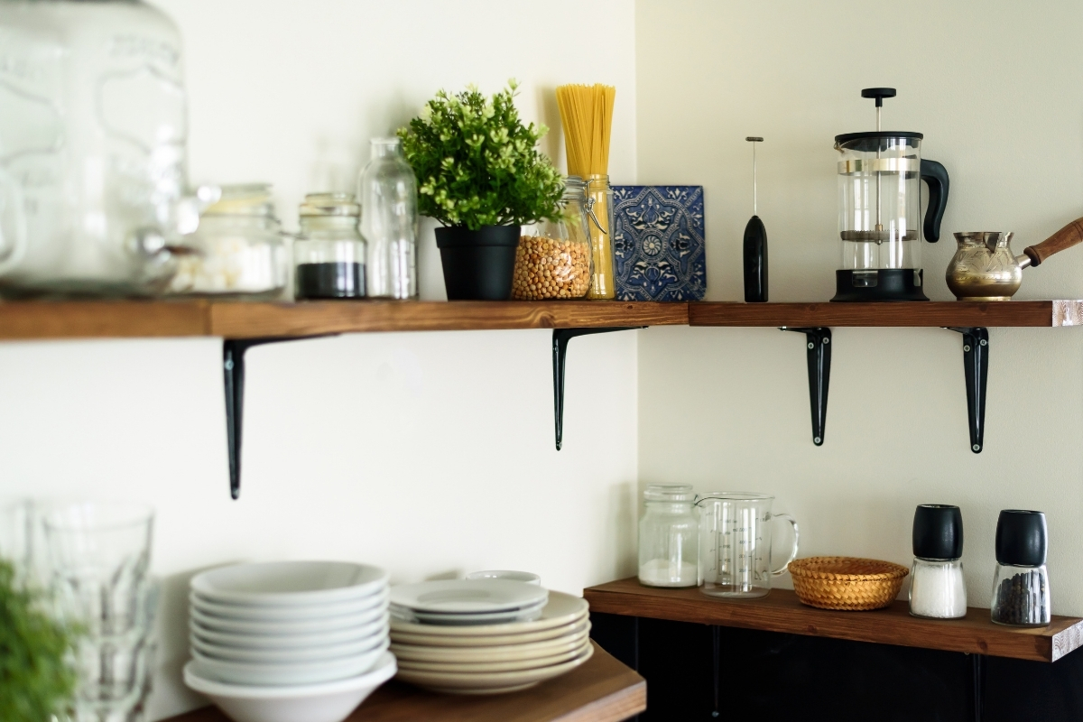 open kitchen shelving styled with dishes plants and ceramics