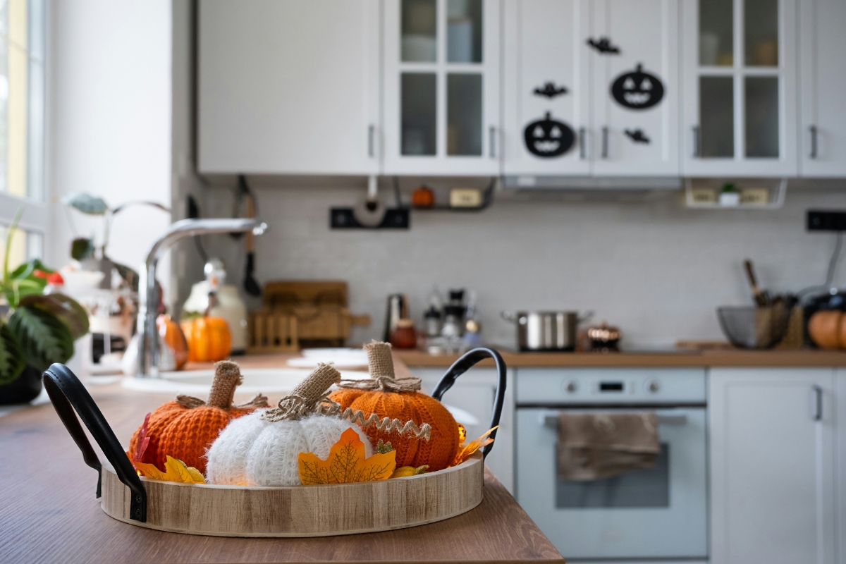 Living room styled with autumn vibes including layered throws, warm-toned cushions, wooden accents, and natural elements like dried flowers for a cozy fall interior