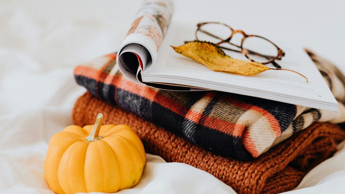 Cozy fall living room styled with deep tone cushions, soft layered blankets, warm lighting, and comfort-focused autumn home decor setup