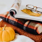 Cozy fall living room styled with deep tone cushions, soft layered blankets, warm lighting, and comfort-focused autumn home decor setup