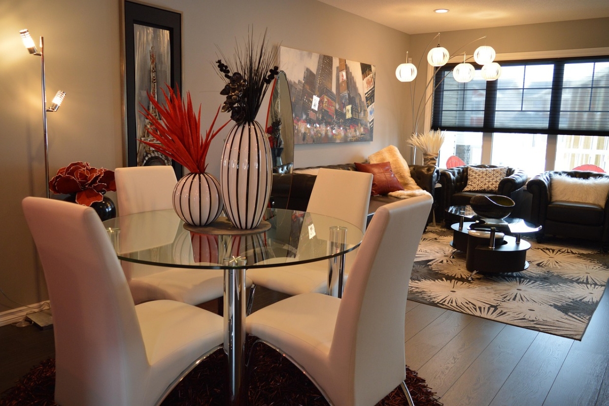 Oversized modern chandelier centered above a rectangular dining table in a contemporary dining room with warm ambient lighting.