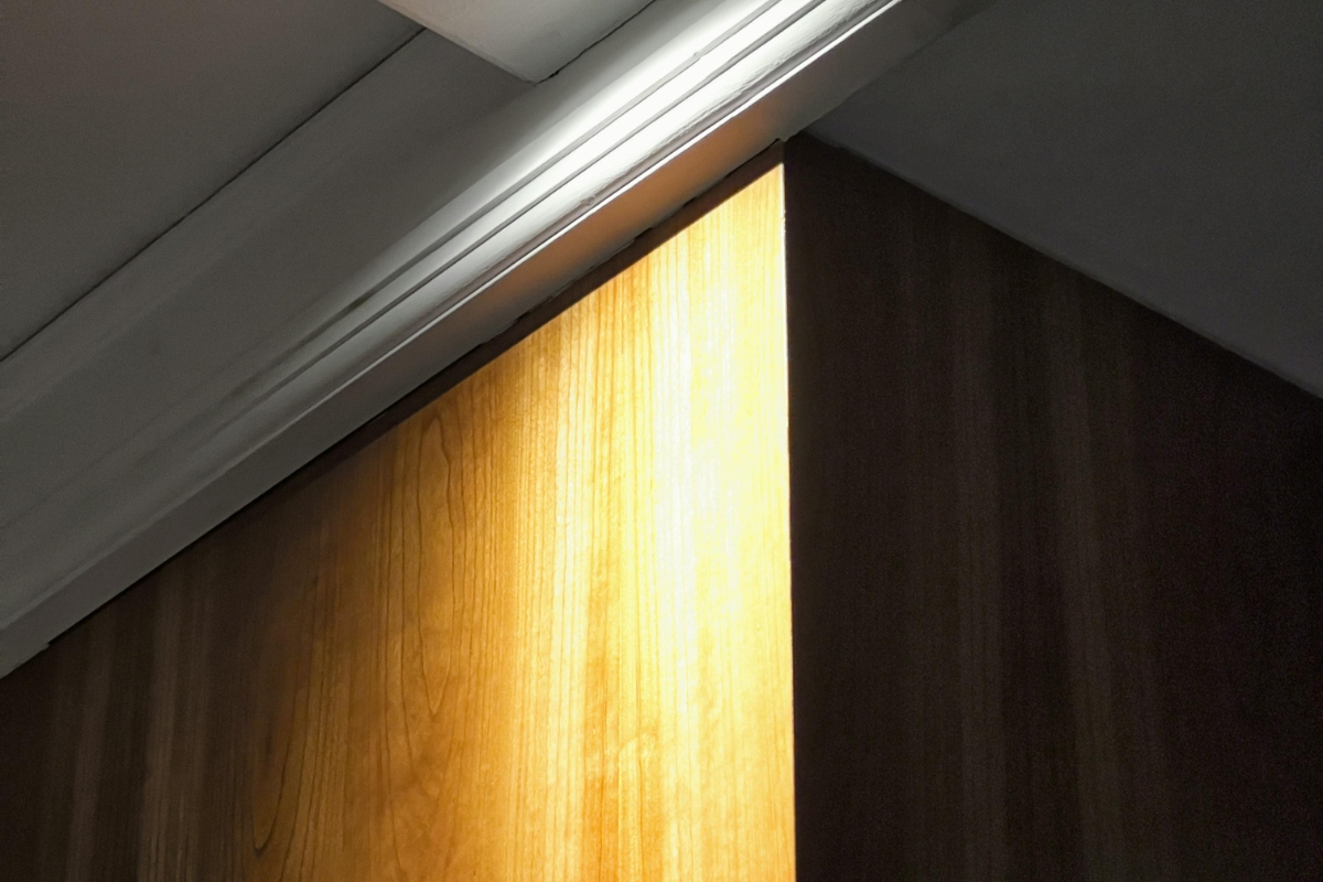 Hidden LED accent lighting highlighting a textured feature wall and decorative shelf in a modern living room interior.