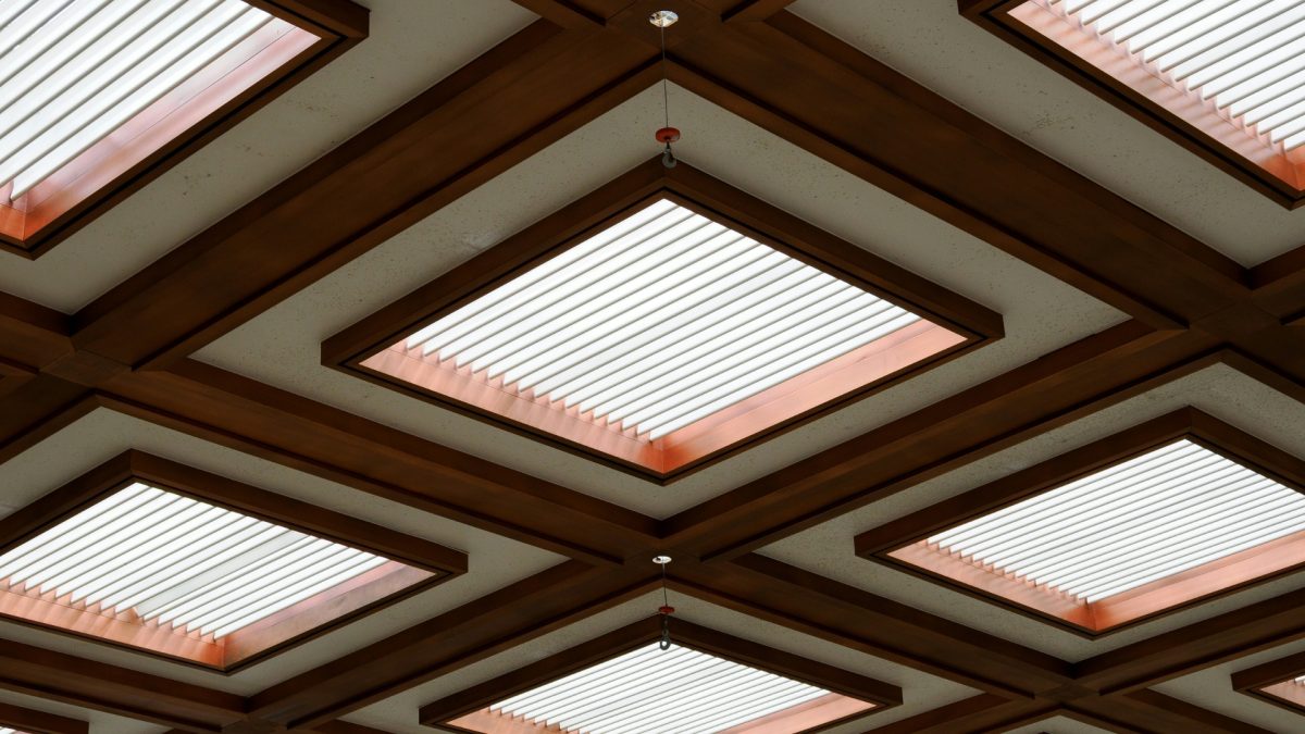 Layered ceiling with wooden beams and warm hidden lighting in modern living room