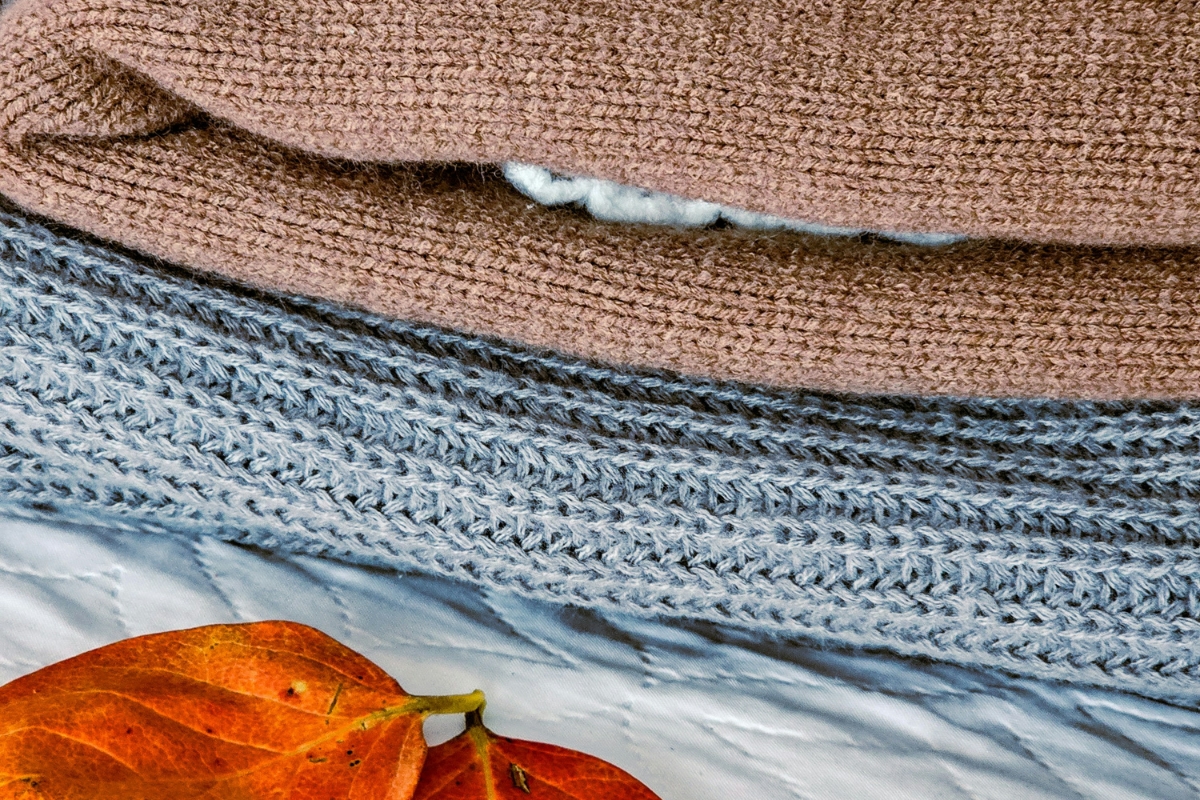 Cozy sofa styled with layered throw blankets, soft cushions, textured fabrics, and warm fall tones creating a comfortable autumn living space
