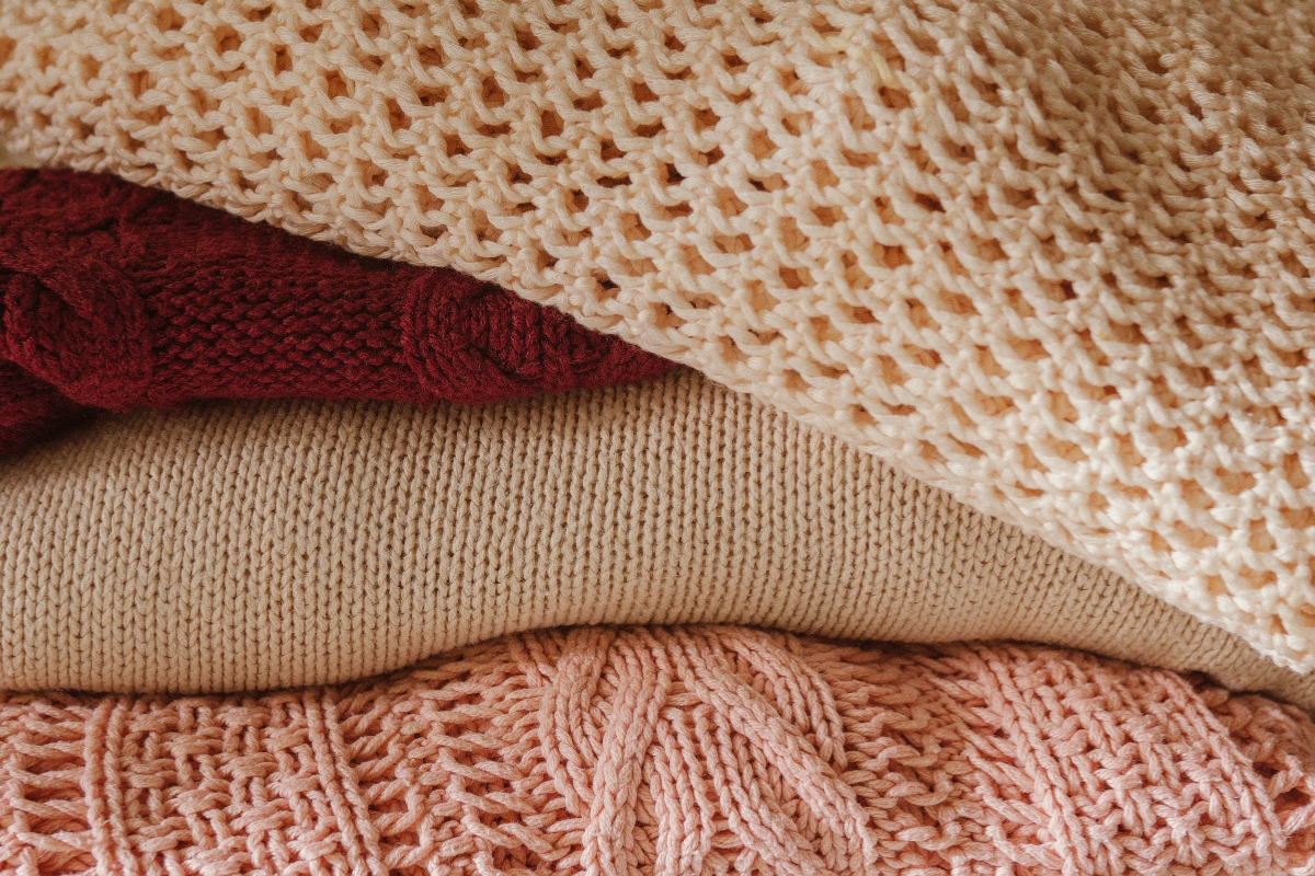 Living room styled with fall textile updates including warm-toned cushions, cozy throw blankets, and layered rugs creating a soft seasonal transition look