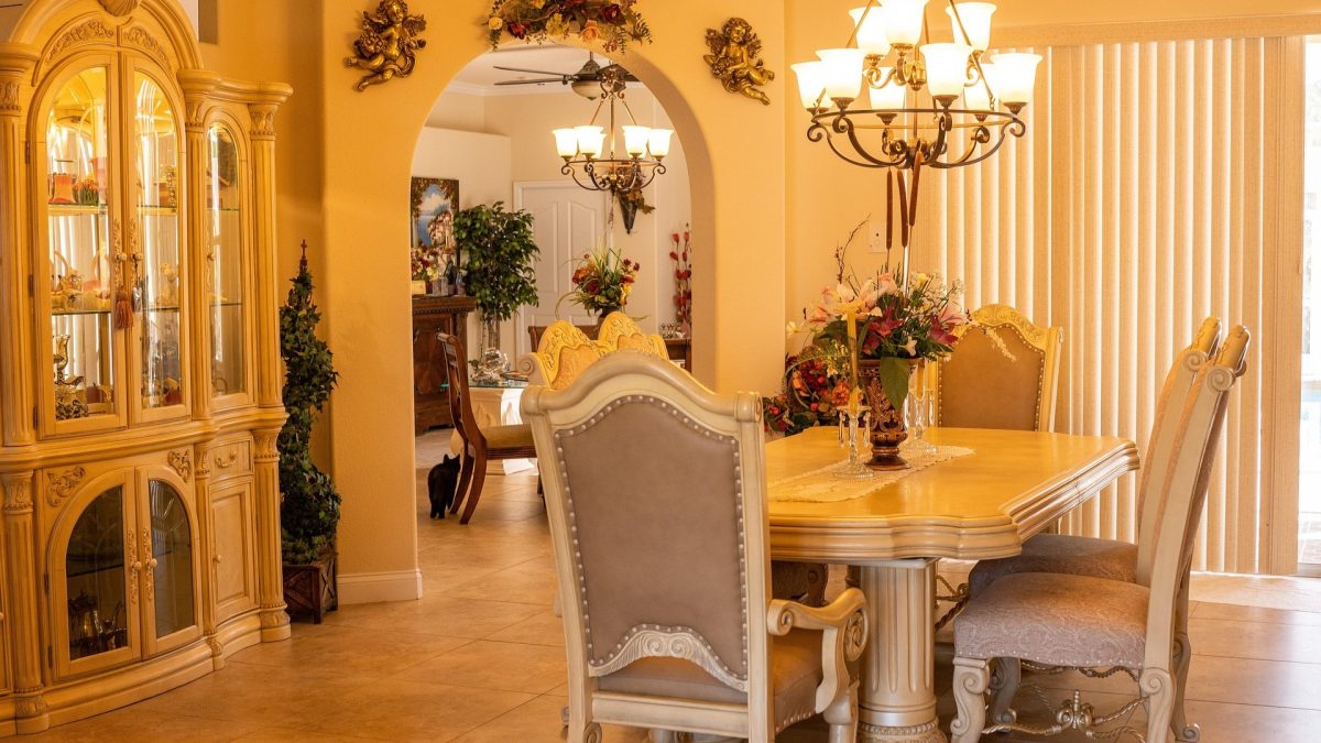 Modern dining room featuring oversized statement chandelier centered above a wooden dining table with warm ambient lighting.