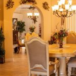 Modern dining room featuring oversized statement chandelier centered above a wooden dining table with warm ambient lighting.