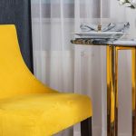 Living room with a neutral timeless sofa and colorful trendy accent chair Wooden dining table paired with bold, modern chairs for style balance