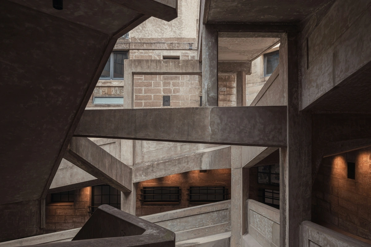 Brutalist architecture interior design space with raw concrete, geometric structures, minimalist furniture, and dopamine decor accents for warmth