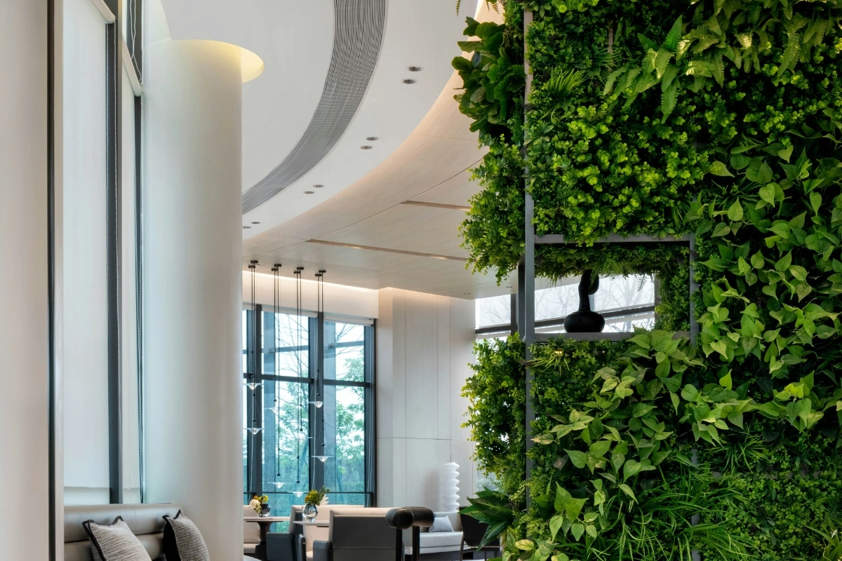 Contemporary biophilic interior design living room with large windows, indoor plants, natural wood furniture, stone textures, and soft natural lighting creating a calm nature-inspired space