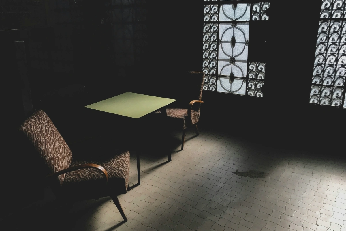 Dark brutalist interior with concrete walls, geometric furniture, moody lighting, and dopamine decor accents to add warmth and contrast