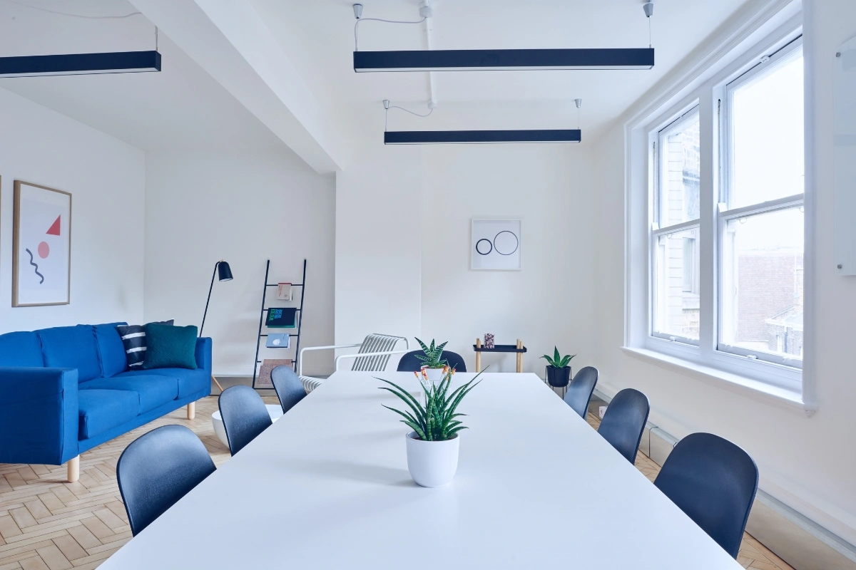 Minimalist brutalist interior with raw concrete, clean geometric furniture, neutral tones, and dopamine decor accents for warmth and visual interest
